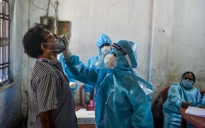 A health worker (C) collects a swab sample from a man for Rapid Antigen Test (RAT) for the COVID-19 coronavirus at a testing center in Siliguri, India, on August 29, 2020. (DIPTENDU DUTTA / AFP)