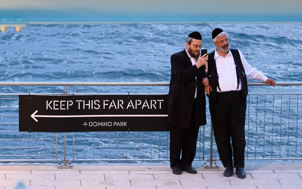 Orthodox men stand next to a social distancing sign in Williamsburg, Brooklyn, July 16, 2020. (Noam Galai/Getty Images/via JTA) Orthodox men stand next to a social distancing sign in Williamsburg, Brooklyn, July 16, 2020. (Noam Galai/Getty Images/via JTA)