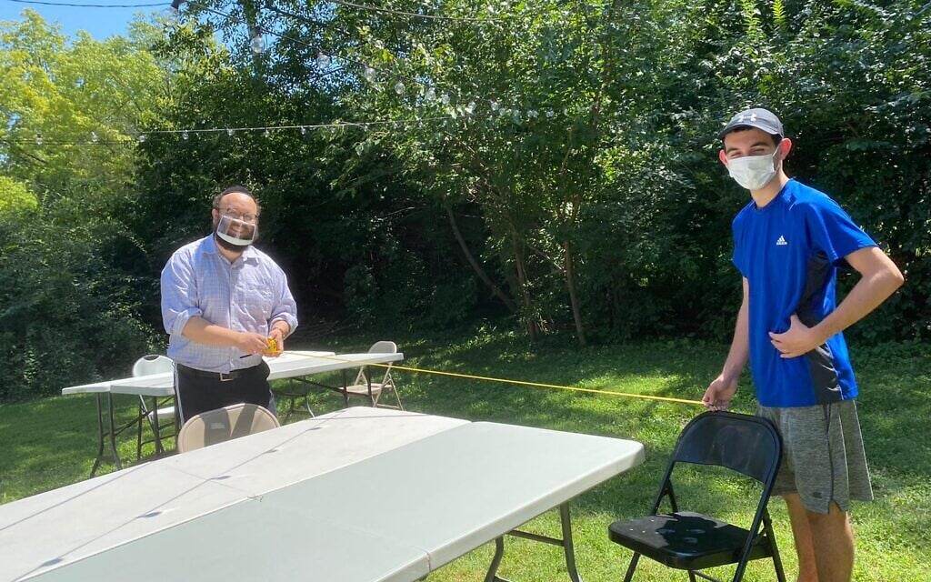 Rabbi Zalman Tiechtel and student Kyle Gold at the University of Kansas measure a 6-foot distance for a socially distanced Shabbat dinner. (Courtesy of Tiechtel/ via JTA)