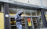 In this March 16, 2020, file photo, a pedestrian wears a face mask while standing outside the High School of Economics & Finance, closed due to coronavirus concerns, in New York (AP Photo/John Minchillo, File)