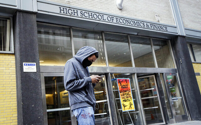 In this March 16, 2020, file photo, a pedestrian wears a face mask while standing outside the High School of Economics & Finance, closed due to coronavirus concerns, in New York (AP Photo/John Minchillo, File) In this March 16, 2020, file photo, a pedestrian wears a face mask while standing outside the High School of Economics & Finance, closed due to coronavirus concerns, in New York (AP Photo/John Minchillo, File)