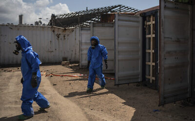 French emergency workers, part of a special unit working with chemicals, walk next to damaged containers near the site of last week's explosion, in the port of Beirut, Lebanon, Monday, Aug. 10, 2020. The unit is identifying potential leaks and securing an area where containers with flammable liquids have been damaged by the blast. (AP Photo/Felipe Dana)