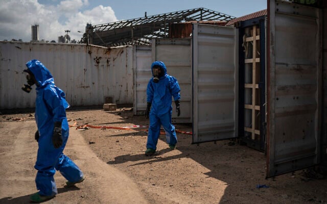 French emergency workers, part of a special unit working with chemicals, walk next to damaged containers near the site of last week's explosion, in the port of Beirut, Lebanon, Monday, Aug. 10, 2020. The unit is identifying potential leaks and securing an area where containers with flammable liquids have been damaged by the blast. (AP Photo/Felipe Dana) French emergency workers, part of a special unit working with chemicals, walk next to damaged containers near the site of last week's explosion, in the port of Beirut, Lebanon, Monday, Aug. 10, 2020. The unit is identifying potential leaks and securing an area where containers with flammable liquids have been damaged by the blast. (AP Photo/Felipe Dana)