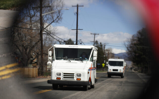 Illustrative: United States Post Office delivery trucks are reflected in the side mirror of a vehicle as postal delivers set off on their daily rounds in Arvada, Colorado, on March 31, 2020. (AP Photo/David Zalubowski, File) Illustrative: United States Post Office delivery trucks are reflected in the side mirror of a vehicle as postal delivers set off on their daily rounds in Arvada, Colorado, on March 31, 2020. (AP Photo/David Zalubowski, File)