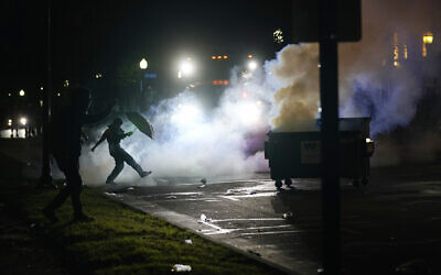 A US protester kicks a smoke canister on August 25, 2020 in Kenosha, Wisconsin. (AP Photo/Morry Gash)