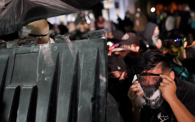 A protester takes cover during clashes outside the Kenosha County Courthouse, August 25, 2020, in Kenosha, Wisconsin. (AP Photo/David Goldman)