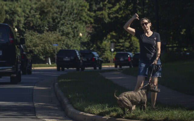 A resident walking her dog gestures as the motorcade of US President Donald Trump drives by towards the Trump National Golf Club in Sterling, Virginia, August 30, 2020. (AP Photo/Manuel Balce Ceneta) A resident walking her dog gestures as the motorcade of US President Donald Trump drives by towards the Trump National Golf Club in Sterling, Virginia, August 30, 2020. (AP Photo/Manuel Balce Ceneta)