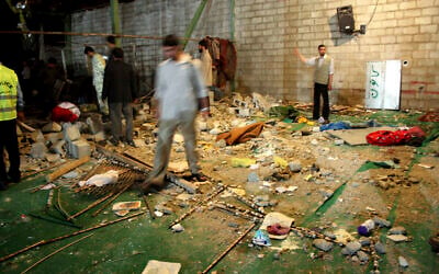 An Iranian police officer and other people look through debris  at the scene of a bomb explosion in a mosque, on April 12 2008 in Shiraz (AP photo)