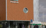 A man walks out of Teva Pharmaceutical facility building in Neot Hovav, Israel, Thursday, Dec. 14, 2017. (AP Photo/Tsafrir Abayov)