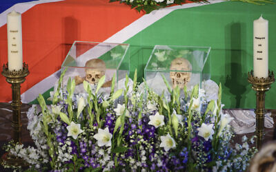 The skulls of two people killed in the  the Herero and Nama uprising between 1904 and 1908 are flanked by candles during a ceremony in Berlin, Aug. 29, 2018 before the repatriation of the remains to Namibia. (Gregor Fischer/dpa via AP)
