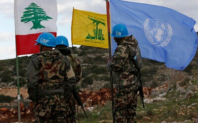 In this December 13, 2018 photo, UN peacekeepers hold their flag while standing next to Hezbollah and Lebanese flags, at the site where Israeli excavators are working, near the southern border village of Mays al-Jabal, Lebanon. (AP/Hussein Malla)