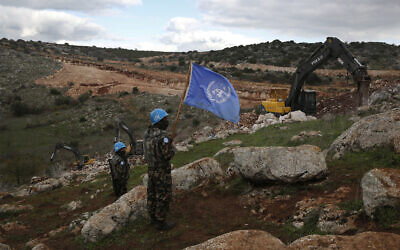 UNIFIL peacekeepers hold their flag, as they observe Israeli excavators attempt to destroy cross-border tunnels dug by Hezbollah, near the southern Lebanese-Israeli border village of Mays al-Jabal, Lebanon, December 13, 2019. (Hussein Malla/AP)