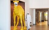 An Emirati wearing a face mask, due to the coronavirus pandemic, walks past a camel statue decorated with a face mask, at the Rove City Centre Hotel in Dubai, United Arab Emirates, July 6, 2020. (AP/Jon Gambrell)