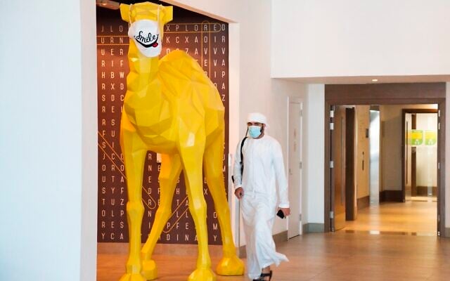 An Emirati wearing a face mask, due to the coronavirus pandemic, walks past a camel statue decorated with a face mask, at the Rove City Centre Hotel in Dubai, United Arab Emirates, July 6, 2020. (AP/Jon Gambrell) An Emirati wearing a face mask, due to the coronavirus pandemic, walks past a camel statue decorated with a face mask, at the Rove City Centre Hotel in Dubai, United Arab Emirates, July 6, 2020. (AP/Jon Gambrell)