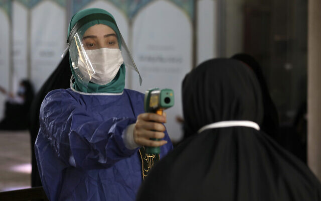 A volunteer wearing protective gear to help prevent the spread of the coronavirus checks temperature of a worshiper as she enters the mosque of Tehran University to pray during Arafat Day, Iran, July 30, 2020. (Vahid Salemi/AP) A volunteer wearing protective gear to help prevent the spread of the coronavirus checks temperature of a worshiper as she enters the mosque of Tehran University to pray during Arafat Day, Iran, July 30, 2020. (Vahid Salemi/AP)