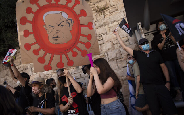 A protester holds a sign depicting Prime Minister Benjamin Netanyahu during a protest a against him outside his residence in Jerusalem, July 31, 2020. (AP/Oded Balilty) A protester holds a sign depicting Prime Minister Benjamin Netanyahu during a protest a against him outside his residence in Jerusalem, July 31, 2020. (AP/Oded Balilty)