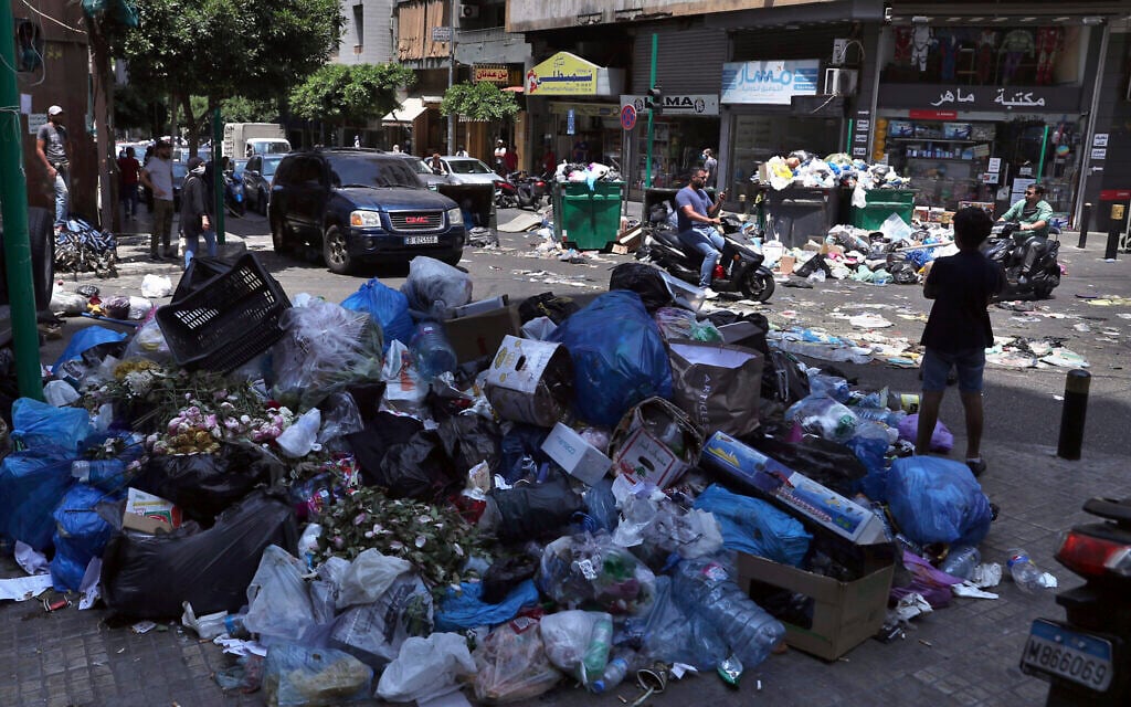In this July 14, 2020, photo, a road is partially blocked with garbage and bins in protest of uncollected trash, in Beirut, Lebanon (AP Photo/Bilal Hussein) In this July 14, 2020, photo, a road is partially blocked with garbage and bins in protest of uncollected trash, in Beirut, Lebanon (AP Photo/Bilal Hussein)