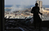 A man stands in a damaged apartment as he looks out at the scene of a massive explosion that hit the seaport of Beirut, Lebanon, August 5, 2020. (Hussein Malla/AP)