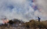 An Israeli worker from the Nature and Parks Authority attempts to extinguish a fire caused by a incendiary balloon launched by Palestinians from the Gaza Strip, on the Israeli side of the border between Israel and Gaza, near Or HaNer Kibbutz, Wednesday, Aug. 12, 2020. (AP/Tsafrir Abayov)