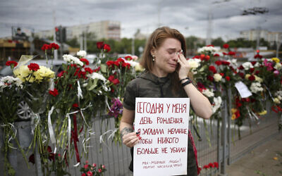 Alina Krus, 26, holds a poster at the place where a protester died amid the clashes in Minsk, Belarus, Aug. 12, 2020 saying "It's my birthday today. I made a wish that no one gets killed. We are peaceful people. Enough with the violence, please."  (AP Photo)