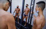 Contestants wearing protective face masks exercise backstage during the National Amateur Body Builders Association competition in Tel Aviv, Israel, Aug. 19, 2020 (AP Photo/Oded Balilty)