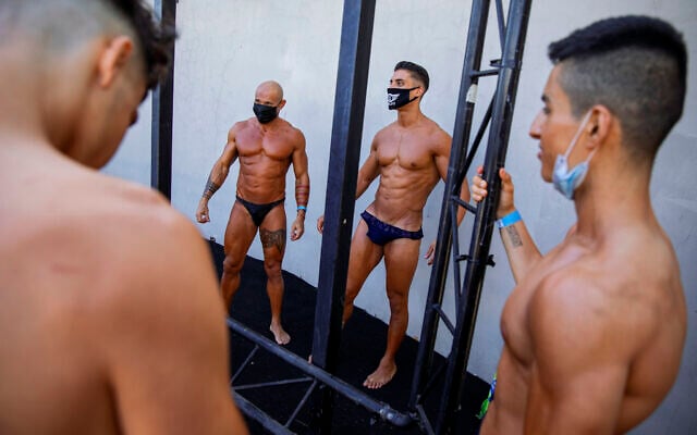 Contestants wearing protective face masks exercise backstage during the National Amateur Body Builders Association competition in Tel Aviv, Israel, Aug. 19, 2020 (AP Photo/Oded Balilty)