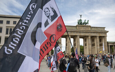 A protestor holds a flag of the German Reich with a picture of US President Donald Trump in front of the Brandenburg Gate before a demonstration against the coronavirus measures by the German Government in Berlin, Germany, Aug. 29, 2020. (Christophe Gateau/dpa via AP)