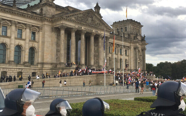 Police officers look to protestors standing on the steps in front of the Reichstag building during a demonstration against the Corona measures in Berlin, Germany, Saturday, Aug. 29, 2020. (Lukas Dubro/dpa via AP) Police officers look to protestors standing on the steps in front of the Reichstag building during a demonstration against the Corona measures in Berlin, Germany, Saturday, Aug. 29, 2020. (Lukas Dubro/dpa via AP)