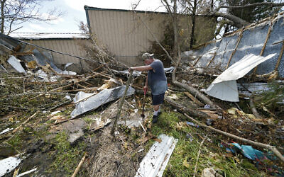 Bradley Beard digs as he searches in vain for his water shutoff valve, next to his heavily damaged home and the destroyed trailer home of his daughter Nicole, in Hackberry, Louisiana, in the aftermath of Hurricane Laura, Aug. 29, 2020. (AP Photo/Gerald Herbert)
