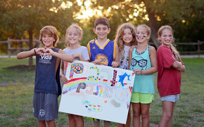 Campers at Camp Young Judaea Texas hold a Hebrew sign that translates as 'We love you.' (Courtesy of authors)