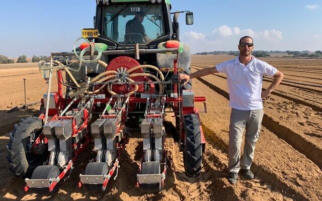 Dotan Borenstein, CEO of SaliCrop, stands next to a tractor distributing carrot seeds for a field trial near the Gaza border, August 23, 2020. (Courtesy) Dotan Borenstein, CEO of SaliCrop, stands next to a tractor distributing carrot seeds for a field trial near the Gaza border, August 23, 2020. (Courtesy)
