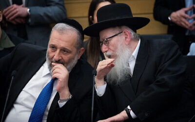 Shas party chairman and Interior Affairs Minister, Aryeh Deri, left, speaks with United Torah Judaism party leader, then health minister, Yaakov Litzman in the Knesset, March 4, 2020. (Yonatan Sindel/ Flash90)