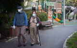 An elderly couple walk in a public park in the Rehavia neighborhood of Jerusalem, April 13, 2020. (Yonatan Sindel/Flash90)