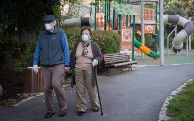 An elderly couple walk in a public park in the Rehavia neighborhood of Jerusalem, April 13, 2020. (Yonatan Sindel/Flash90)
