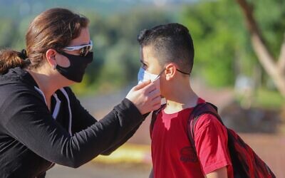 Israeli children wear face masks on their way to school in Moshav Yashresh, on May 3, 2020. (Yossi Aloni/Flash90)