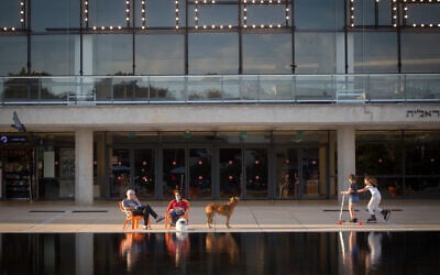 People sit outside the closed Habima Theatre in Tel Aviv, May 26, 2020. (Miriam Alster/Flash90)