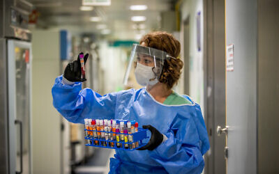 A technician carries out a diagnostic test for coronavirus in a lab at the Ichilov Hospital in Tel Aviv on August 3, 2020. (Yossi Aloni/Flash90)