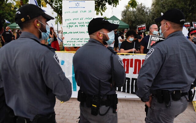 Police officers stand in front of protesters demonstrating against Prime Minister Benjamin Netanyahu near his home in the coastal town of Caesarea on August 8, 2020. (Meir Vaknin/Flash90) Police officers stand in front of protesters demonstrating against Prime Minister Benjamin Netanyahu near his home in the coastal town of Caesarea on August 8, 2020. (Meir Vaknin/Flash90)