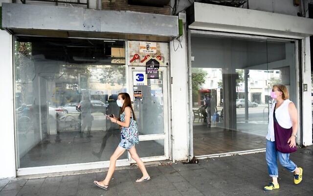 People walk next to empty shops in Tel Aviv on August 11, 2020. (Flash90) People walk next to empty shops in Tel Aviv on August 11, 2020. (Flash90)