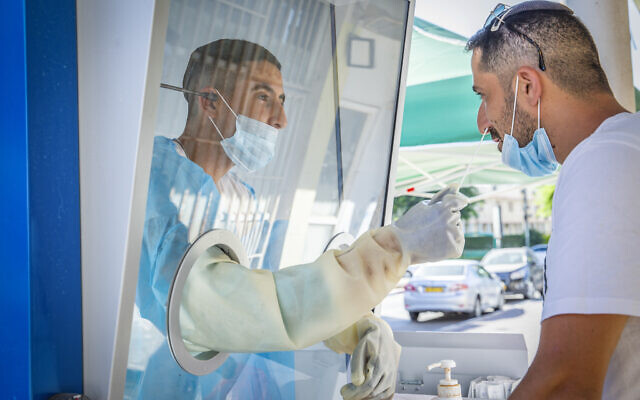 A healthcare worker takes samples from Israelis to test them for the coronavirus at a mobile testing station in the central city of Ramle, August 18, 2020. (Yossi Aloni/Flash90) A healthcare worker takes samples from Israelis to test them for the coronavirus at a mobile testing station in the central city of Ramle, August 18, 2020. (Yossi Aloni/Flash90)