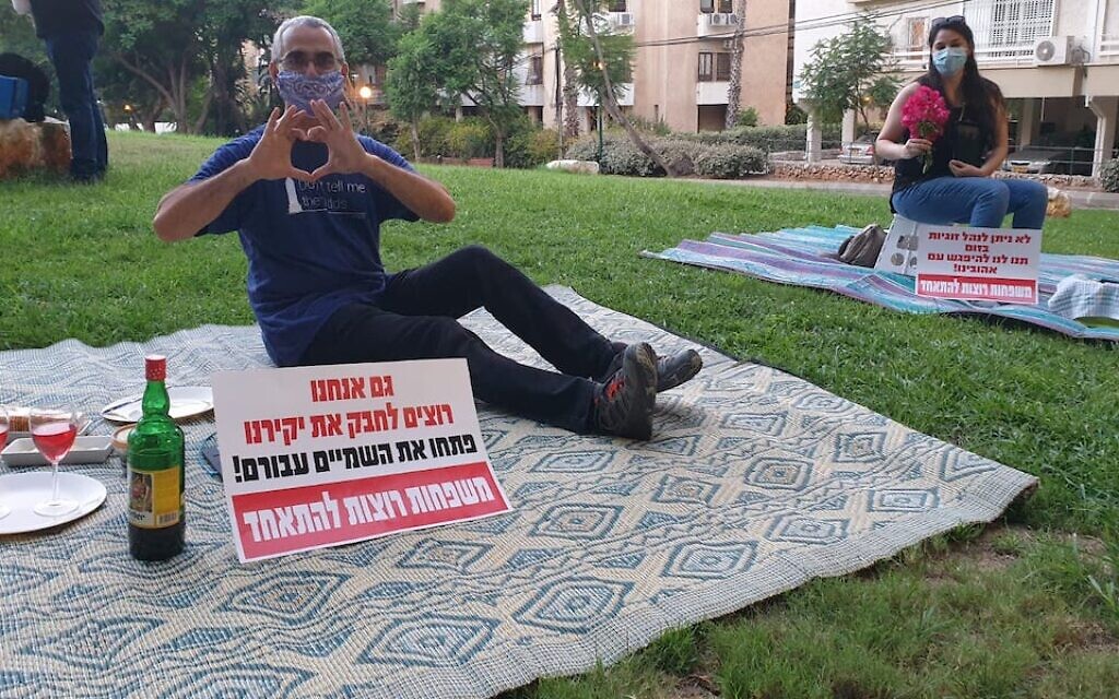 Israelis protest being separated from their significant others outside the residence of the foreign minister by having solo romantic picnics on the eve of Tu B'Av, the Jewish day celebrating love. The signs read, "We also want to embrace our loved ones. Open the skies for them. Families want to be together." (Courtesy: Plia Kettner via JTA) Israelis protest being separated from their significant others outside the residence of the foreign minister by having solo romantic picnics on the eve of Tu B'Av, the Jewish day celebrating love. The signs read, "We also want to embrace our loved ones. Open the skies for them. Families want to be together." (Courtesy: Plia Kettner via JTA)