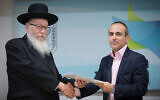 Then deputy health minister Yaakov Litzman, left, shakes hands with Ronni Gamzu during a press conference at the Health Ministry in Jerusalem on January 3, 2019. (Noam Revkin Fenton/Flash90/File)