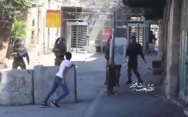 A still from a video shows a Palestinian youth hurling rocks at IDF soldiers in Hebron at close range, August 29, 2020 (video screenshot) A still from a video shows a Palestinian youth hurling rocks at IDF soldiers in Hebron at close range, August 29, 2020 (video screenshot)