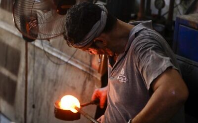 A glassblower forms glass at factory, which is recycling the broken glass as a result of the Beirut explosion, in the northern Lebanese port city of Tripoli on August 25, 2020 (JOSEPH EID / AFP)