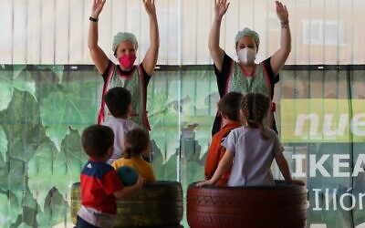 In this file photo taken on June 10, 2020 teachers wearing face masks gesture opposite children at the Palotes pre-school in Valladolid, Spain (CESAR MANSO / AFP)