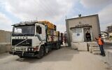 A Palestinian policeman waves on a truck as it enters through the Kerem Shalom crossing into the Gaza Strip on September 1, 2020, after a Qatari-mediated deal with Israel. (SAID KHATIB / AFP)