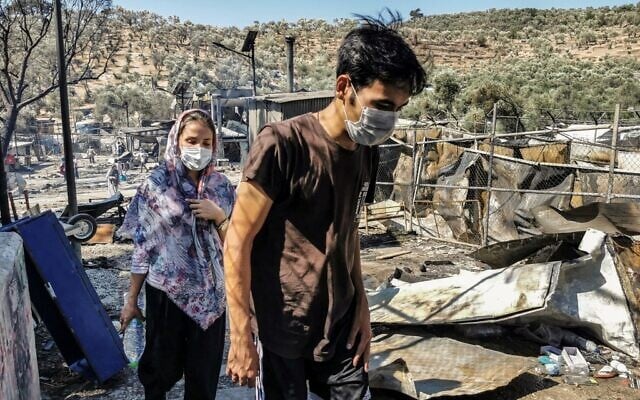 Migrants walk inside the burnt Moria Camp on the Greek island of Lesbos on September 9, 2020, after a major fire. (Anthi PAZIANOU / AFP) Migrants walk inside the burnt Moria Camp on the Greek island of Lesbos on September 9, 2020, after a major fire. (Anthi PAZIANOU / AFP)