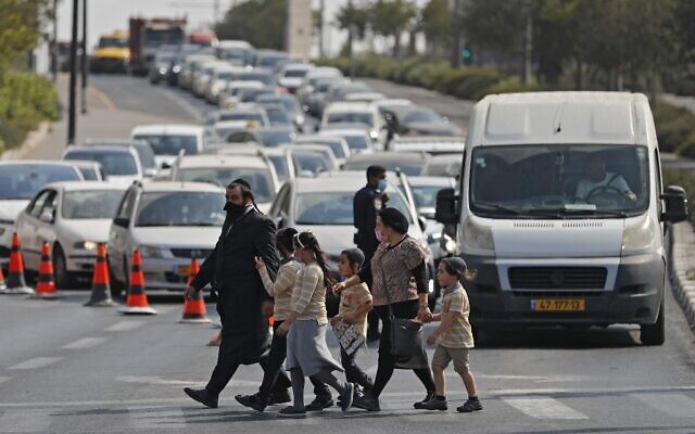 People cross a street in Jerusalem as police man a checkpoint to enforce a new lockdown amid the COVID-19 pandemic, on September 18, 2020 (Ahmad GHARABLI / AFP) People cross a street in Jerusalem as police man a checkpoint to enforce a new lockdown amid the COVID-19 pandemic, on September 18, 2020 (Ahmad GHARABLI / AFP)