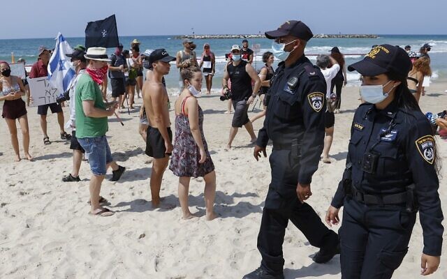 Police officers patrol on a beach as Israelis demonstrate in Tel Aviv against the nationwide coronavirus lockdown, on September 19, 2020. (Jack Guez/AFP)