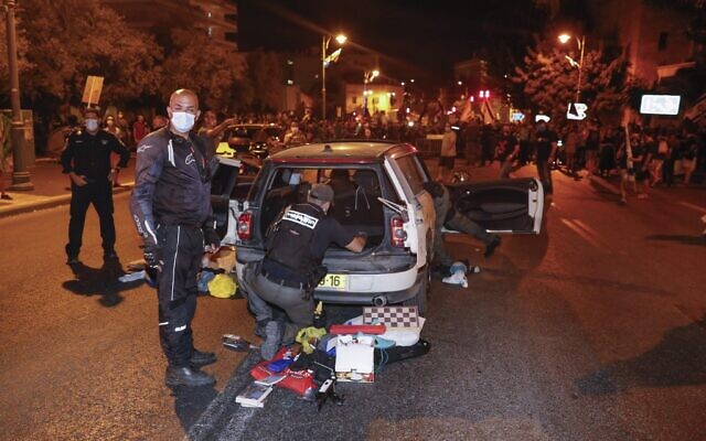 Israeli police officers search a car after the driver reportedly drove his car at speed towards security barricades set around an anti-government demonstration, in front of Prime Minister Benjamin Netanyahu's residence in Jerusalem, on September 20, 2020. (Ahmad GHARABLI / AFP)